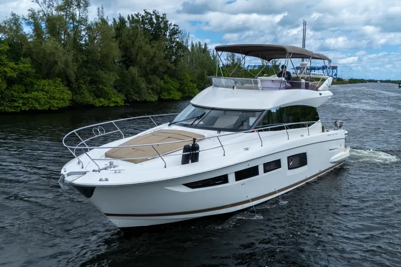  Yacht Photos Pics 2012 Prestige Flybridge yacht cruising on a scenic waterway with lush greenery.