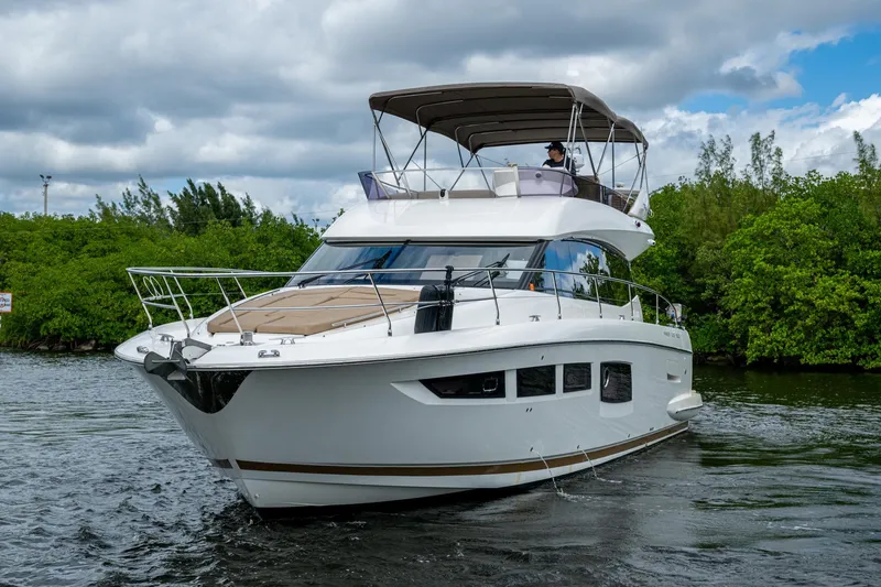  Yacht Photos Pics 2012 Prestige Flybridge yacht cruising on a river with lush greenery.