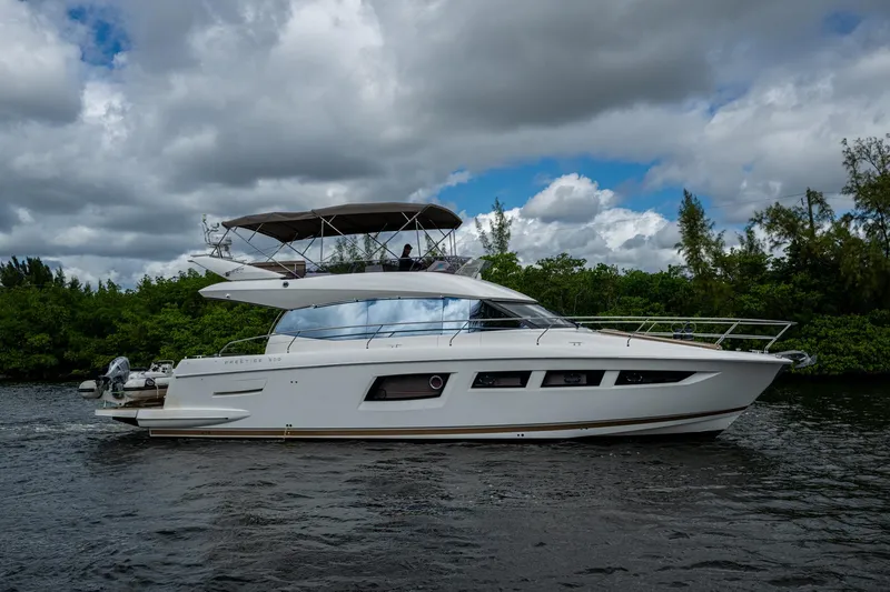  Yacht Photos Pics 2012 Prestige Flybridge yacht cruising on a scenic waterway under cloudy skies.