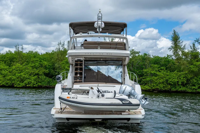  Yacht Photos Pics 2012 Prestige Flybridge yacht with tender, cruising on a scenic waterway.