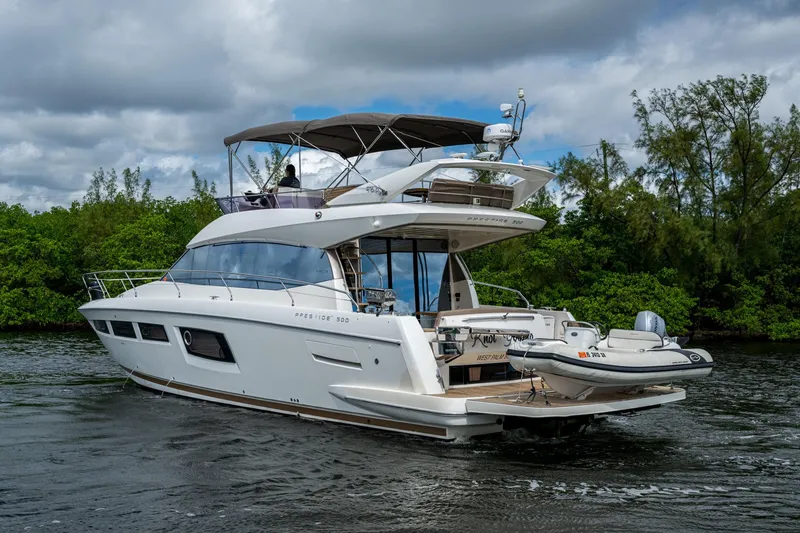  Yacht Photos Pics 2012 Prestige Flybridge yacht cruising on a river with lush greenery in the background.