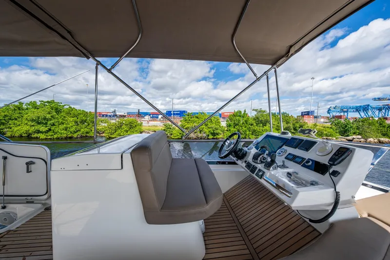  Yacht Photos Pics 2012 Prestige Flybridge yacht helm with modern controls, overlooking lush greenery and industrial backdrop.