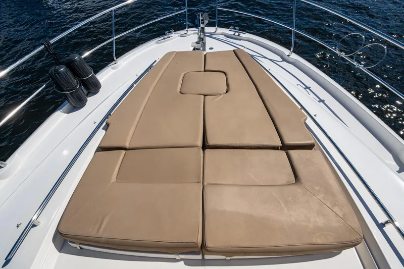  Yacht Photos Pics Prestige Flybridge 2012 yacht with tan sunbathing cushions on deck, surrounded by water.