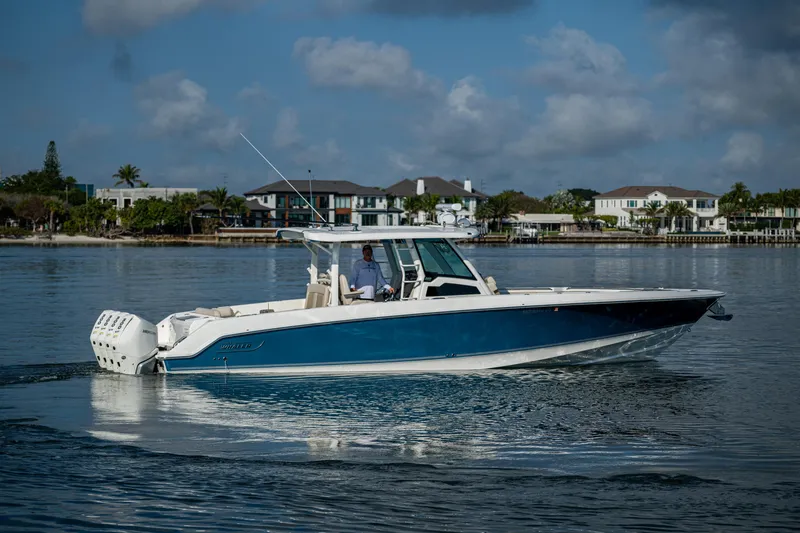  Yacht Photos Pics 2024 Boston Whaler 380 Outrage cruising on calm waters near waterfront homes.