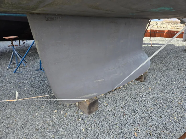 Surprise Yacht Photos Pics Keel of a 2007 Beneteau 49 sailboat on gravel, supported by stands.
