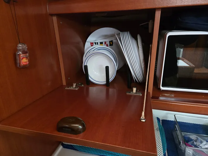 Surprise Yacht Photos Pics Wooden cabinet with plates and a microwave on a 2007 Beneteau 49 yacht.