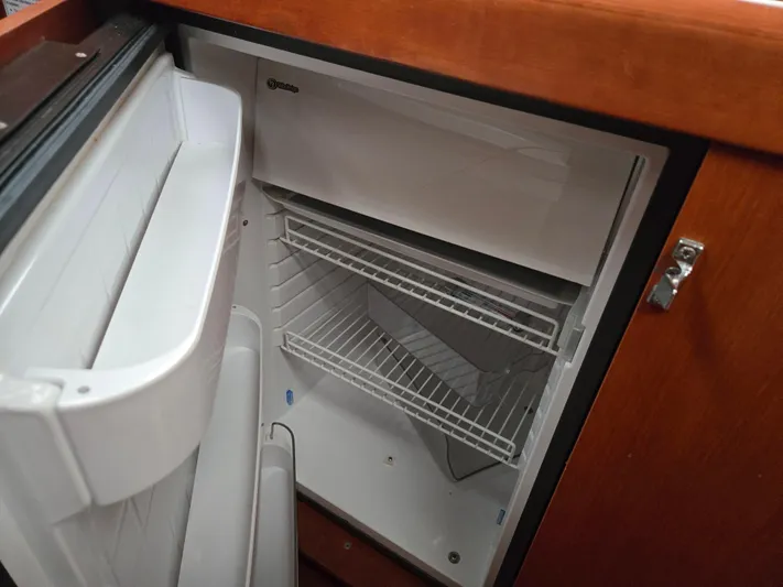 Surprise Yacht Photos Pics Open refrigerator inside a 2007 Beneteau 49 yacht, featuring wire shelves and wooden cabinetry.