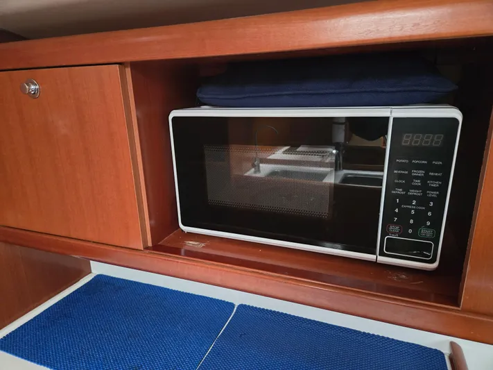 Surprise Yacht Photos Pics Microwave in 2007 Beneteau 49 yacht kitchen, wooden cabinetry, blue mats.