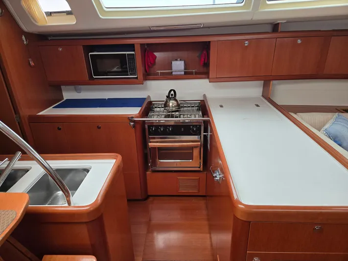 Surprise Yacht Photos Pics Interior of 2007 Beneteau 49 yacht kitchen with stove, sink, and wooden cabinetry.