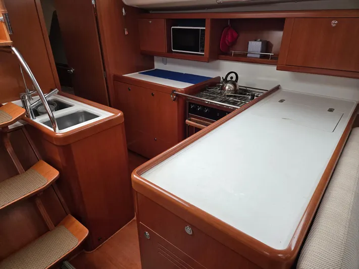 Surprise Yacht Photos Pics Interior of 2007 Beneteau 49 yacht kitchen with wooden cabinetry and modern appliances.