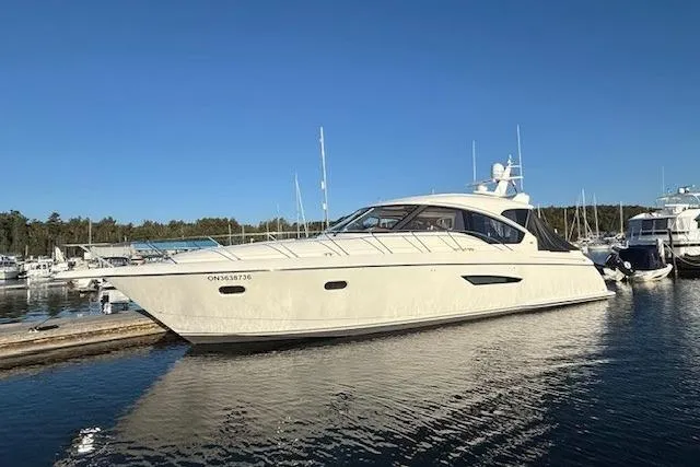 Jesse James Yacht Photos Pics 2011 Tiara Yachts 5800 Sovran in marina, sleek design, calm water, clear sky.