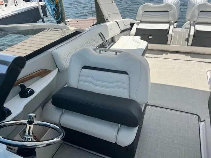  Yacht Photos Pics 2024 Regal 29 boat interior with white seating and steering wheel, docked by the water.