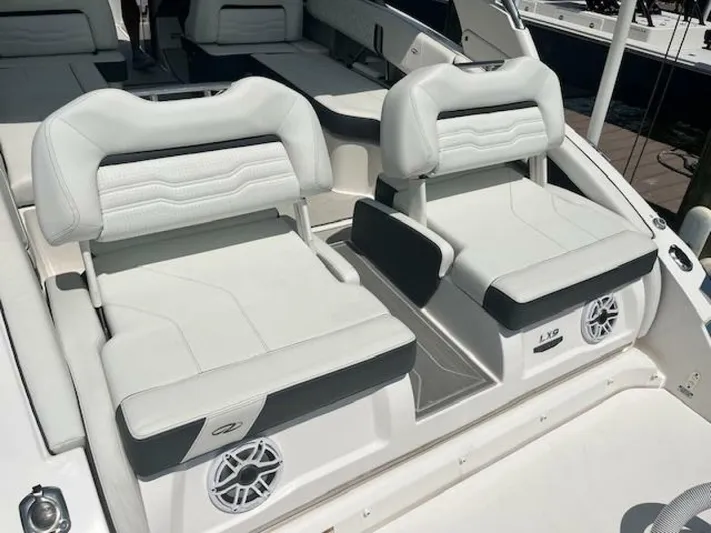  Yacht Photos Pics 2024 Regal 29 boat interior with white cushioned seats and built-in speakers.