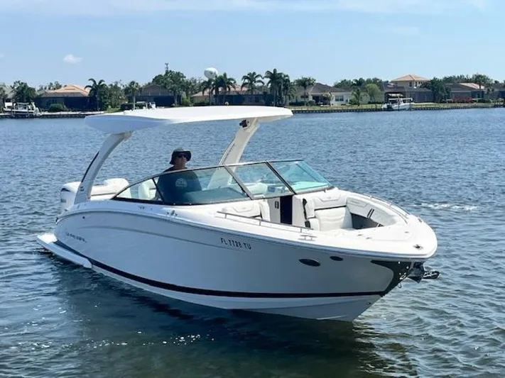  Yacht Photos Pics 2024 Regal 29 boat cruising on a sunny lake with houses in the background.