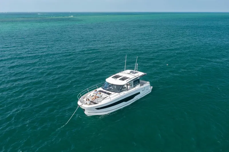  Yacht Photos Pics 2026 Jeanneau NC 1295 Weekender yacht anchored on clear blue ocean waters.