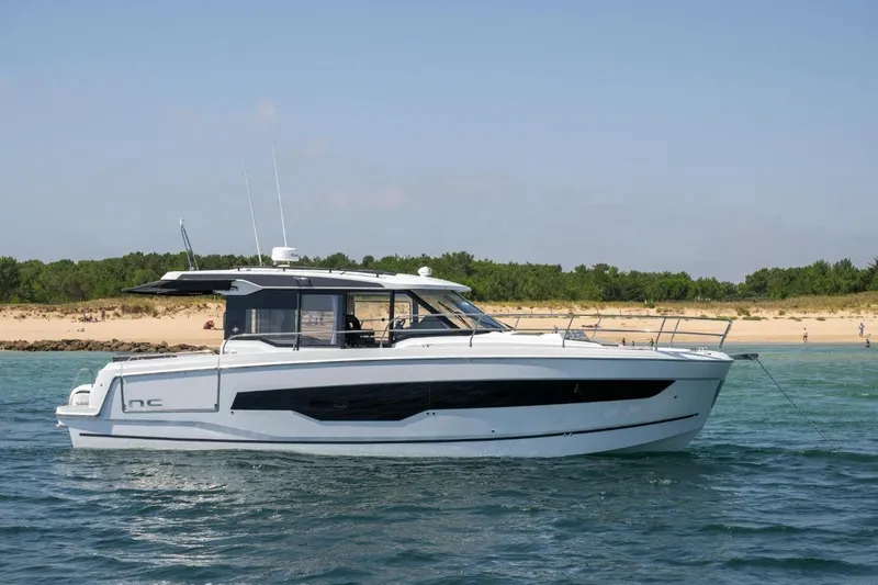  Yacht Photos Pics 2026 Jeanneau NC 1295 Weekender yacht anchored near a sandy beach.