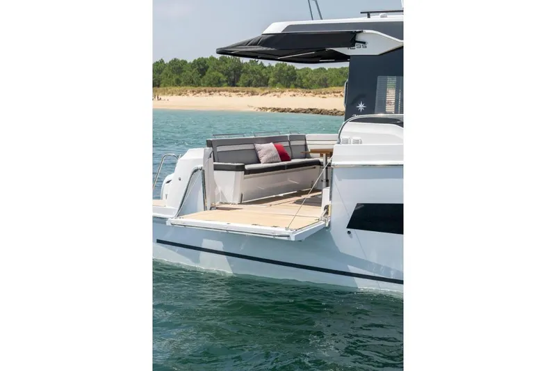  Yacht Photos Pics 2026 Jeanneau NC 1295 Weekender yacht with open deck, docked near a sandy beach.