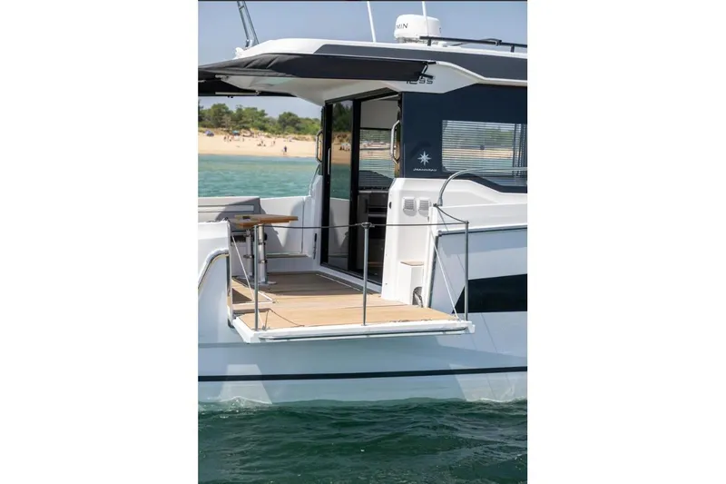  Yacht Photos Pics 2026 Jeanneau NC 1295 Weekender yacht with open deck, near a sandy beach.