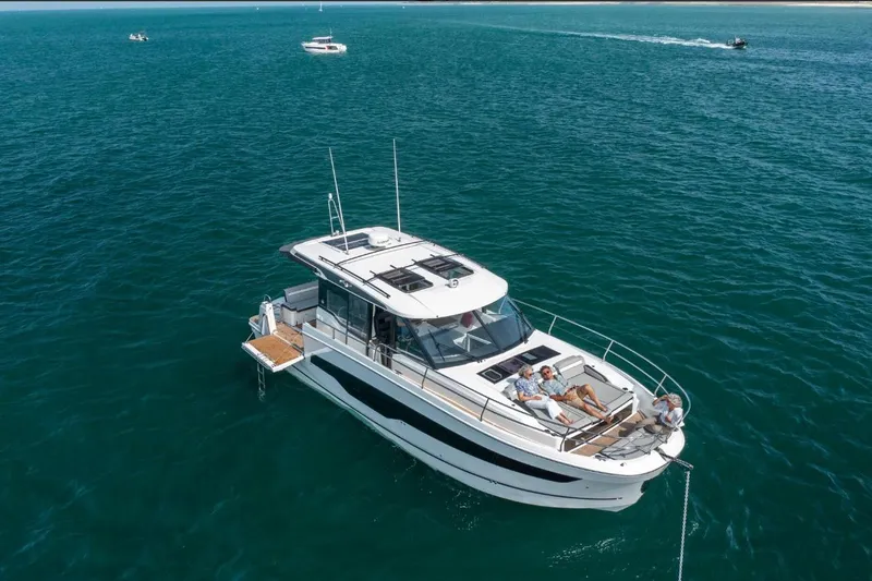  Yacht Photos Pics 2026 Jeanneau NC 1295 Weekender cruising on open water with passengers relaxing on deck.