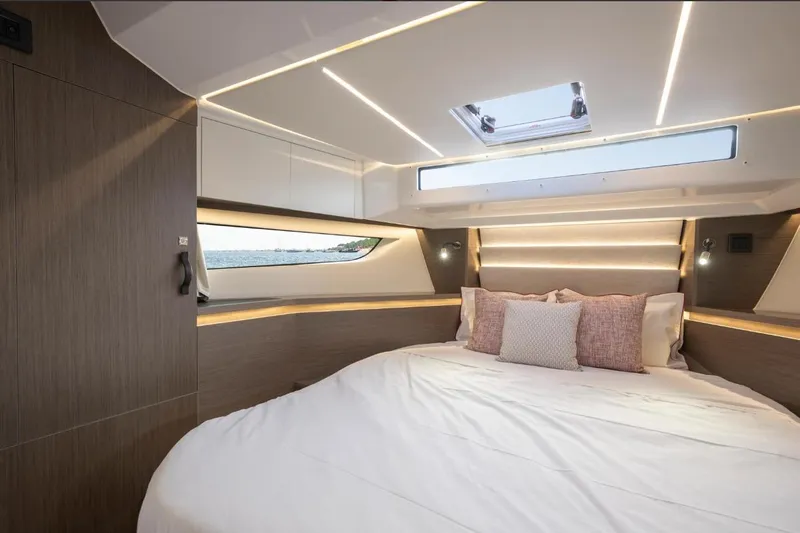  Yacht Photos Pics Luxurious cabin interior of 2026 Jeanneau NC 1295 Weekender with modern design and cozy bedding.