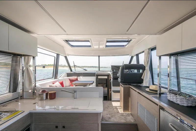  Yacht Photos Pics Luxurious interior of 2026 Jeanneau NC 1295 Weekender yacht with modern kitchen and seating area.