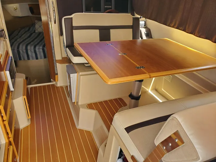  Yacht Photos Pics Interior of 2016 Cutwater 30 Command Bridge with wood table and seating area.