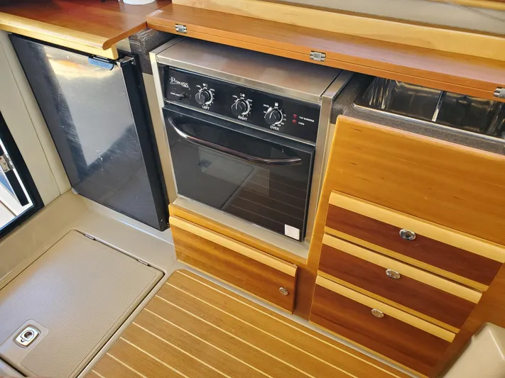  Yacht Photos Pics 2016 Cutwater 30 Command Bridge kitchen with oven, fridge, and wooden cabinetry.