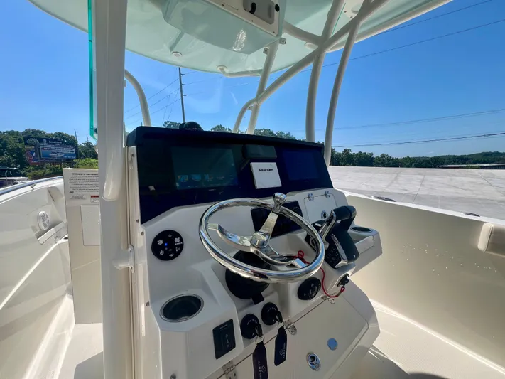  Yacht Photos Pics 2023 Sailfish 290 CC boat dashboard with steering wheel and controls under clear blue sky.