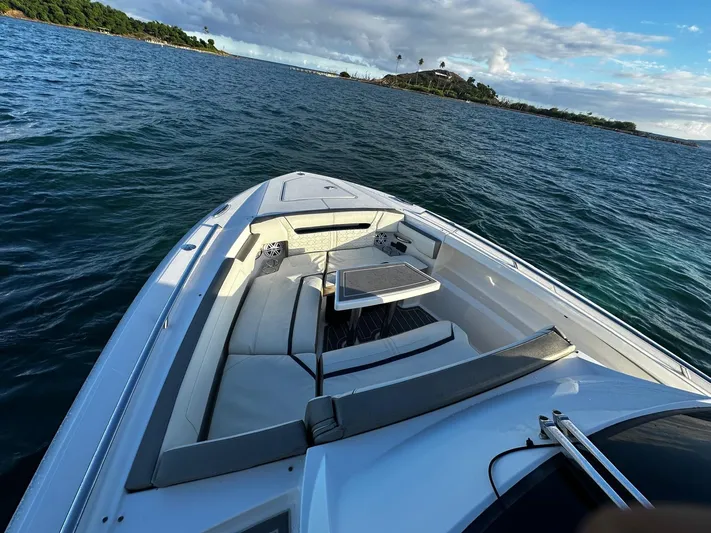  Yacht Photos Pics 2023 Tiara Yachts 34 LS cruising on scenic ocean waters under a partly cloudy sky.