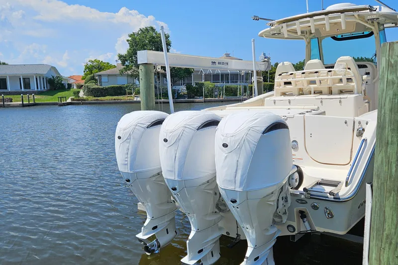  Yacht Photos Pics 2022 Grady-White Canyon 306 boat with triple outboard engines docked by waterfront homes.