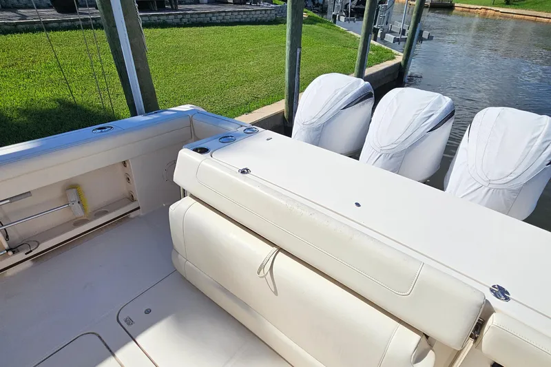  Yacht Photos Pics 2022 Grady-White Canyon 306 boat with covered engines docked by a grassy shore.