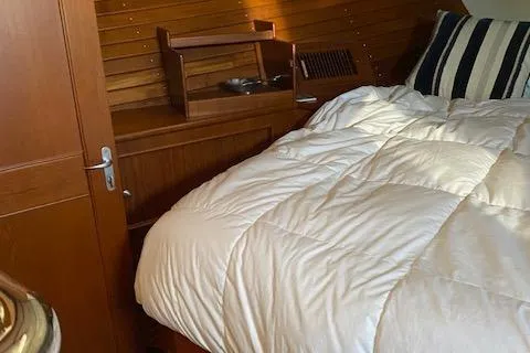 Contessa Yacht Photos Pics Cozy cabin interior of 2001 Grand Banks 49 Eastbay SX with wooden paneling and bedding.