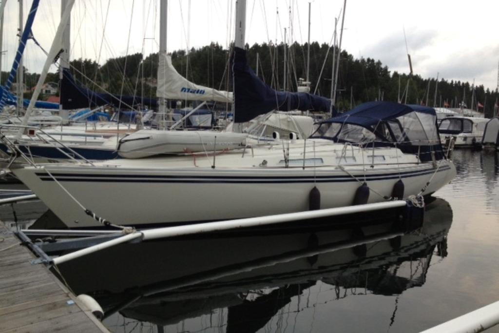 Sailboat docked at marina, Scanner 391 model, 2006, with blue covers and calm water reflection.