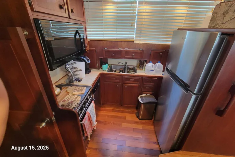'charisma' Yacht Photos Pics Compact kitchen in 1985 Chris-Craft 500 Constellation yacht with wooden cabinets and modern appliances.