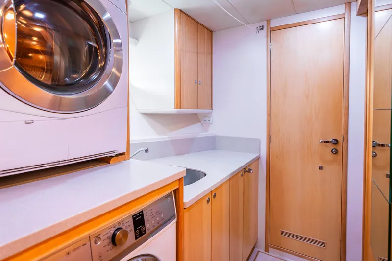 Texas T Yacht Photos Pics Laundry room in 2009 Sulis Marine Expedition Yacht with washer, dryer, and wooden cabinetry.