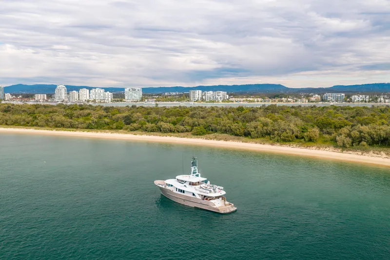 Texas T Yacht Photos Pics Custom 2009 Sulis Marine Expedition Yacht near scenic coastline with city skyline backdrop.