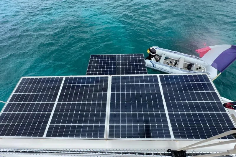 Sixtus Yacht Photos Pics Solar panels on Lagoon 450 s catamaran, 2016 model, with dinghy in turquoise water.