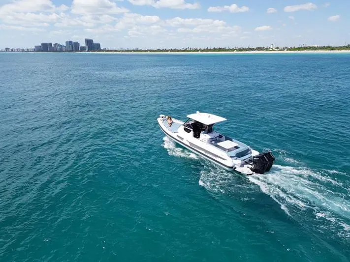  Yacht Photos Pics 2025 Ranieri CAYMAN 38.0 EXECUTIVE cruising on clear blue waters near a distant cityscape.