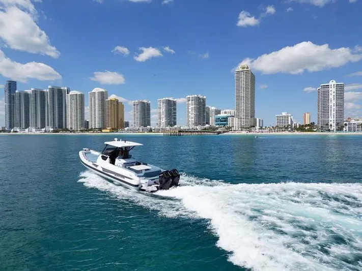  Yacht Photos Pics Ranieri CAYMAN 38.0 EXECUTIVE 2025 cruising near a city skyline on a sunny day.