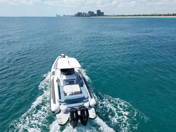  Yacht Photos Pics 2025 Ranieri CAYMAN 38.0 EXECUTIVE cruising on open water near a distant city skyline.