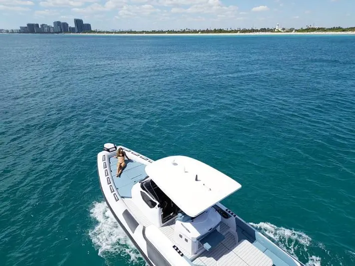  Yacht Photos Pics 2025 Ranieri CAYMAN 38.0 EXECUTIVE cruising on clear blue waters near a distant shoreline.