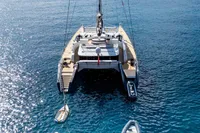 Luxury catamaran by Compositeworks (2006) with paddleboards and dinghy in serene ocean setting.
