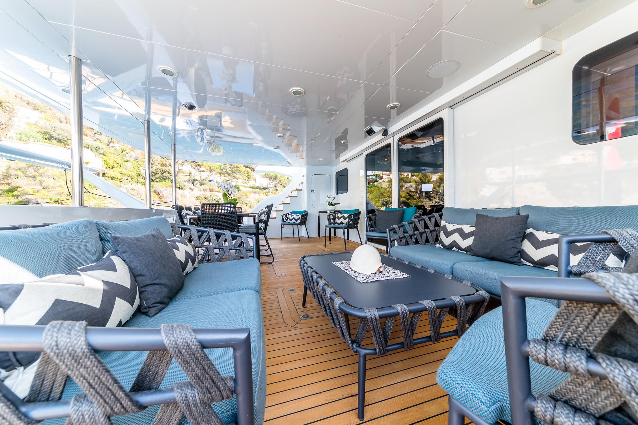 Luxurious yacht deck with blue seating, chevron pillows, and wooden flooring, Custom Compositeworks 2006.