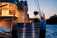 Luxury yacht at sunset, Custom Compositeworks 2006, illuminated steps, serene water backdrop.