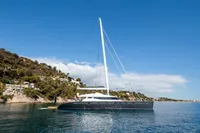 Luxurious 2006 Custom Compositeworks yacht sailing near a scenic coastline under a clear blue sky.