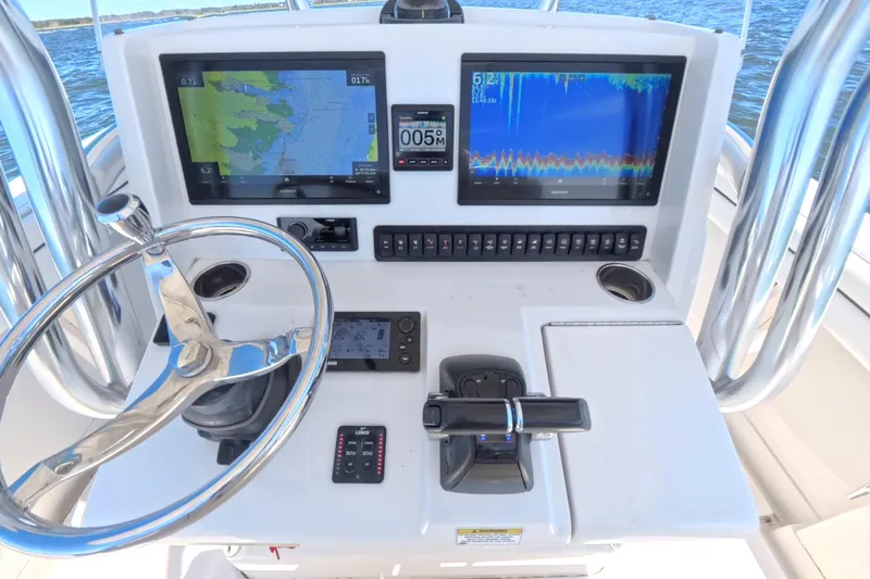  Yacht Photos Pics Control panel of a 2014 Jupiter 30 FS boat with navigation screens and steering wheel.