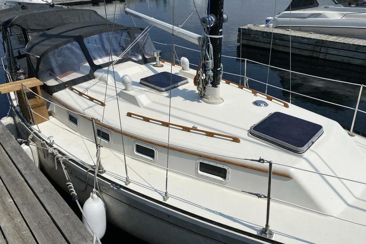 1984 Aloha 34 sailboat docked, featuring a sleek white deck and black canopy.