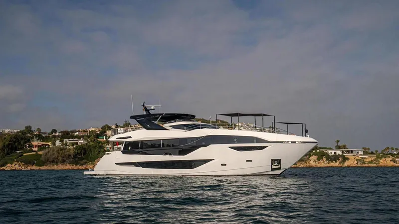 Contessa Yacht Photos Pics 2024 Sunseeker 100' Yacht cruising near a scenic coastline under a clear sky.