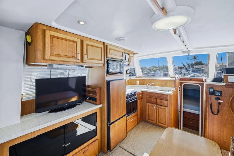  Yacht Photos Pics Interior of 1998 Mainship 350 Trawler with kitchen, TV, and wooden cabinetry.