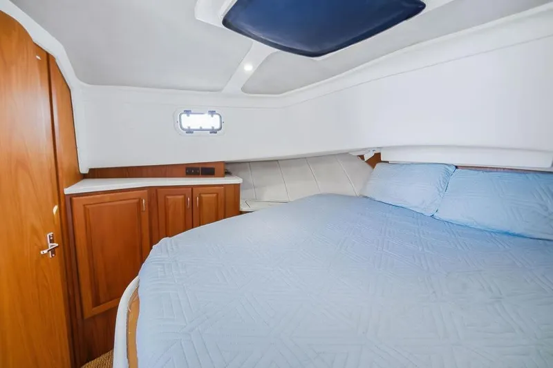  Yacht Photos Pics Cozy cabin interior of 1998 Mainship 350 Trawler with blue bedding and wooden cabinetry.